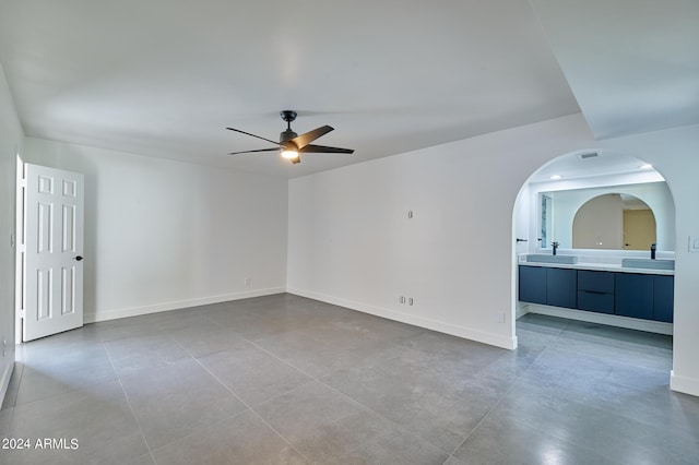 tiled empty room featuring sink and ceiling fan