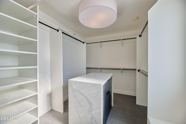 walk in closet with tile patterned floors and a barn door