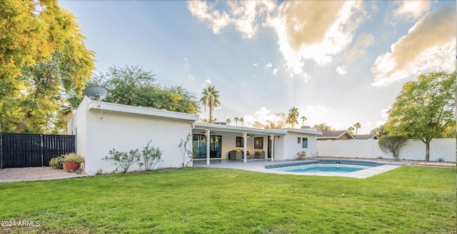 back of house featuring a patio, a fenced in pool, and a lawn