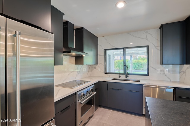 kitchen with sink, wall chimney range hood, dark stone countertops, stainless steel appliances, and backsplash