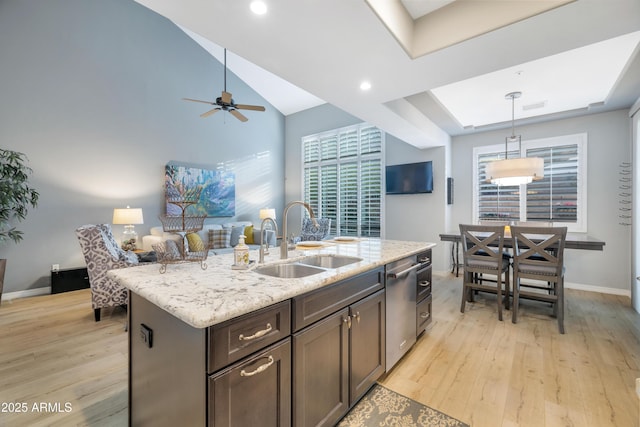 kitchen with ceiling fan, sink, pendant lighting, light hardwood / wood-style flooring, and an island with sink