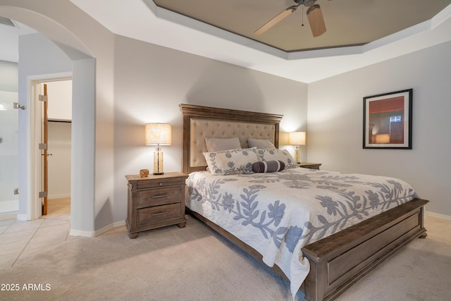 bedroom featuring ceiling fan, a raised ceiling, and light colored carpet