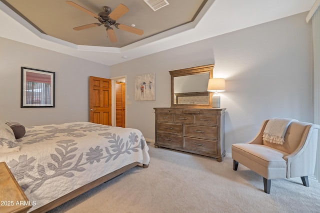 carpeted bedroom with a tray ceiling and ceiling fan