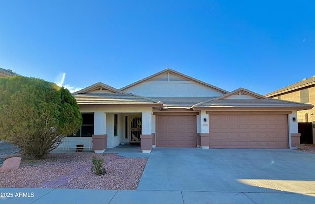 ranch-style house with a tile roof, concrete driveway, a garage, and stucco siding