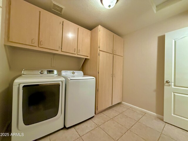 laundry room with visible vents, independent washer and dryer, cabinet space, light tile patterned floors, and baseboards