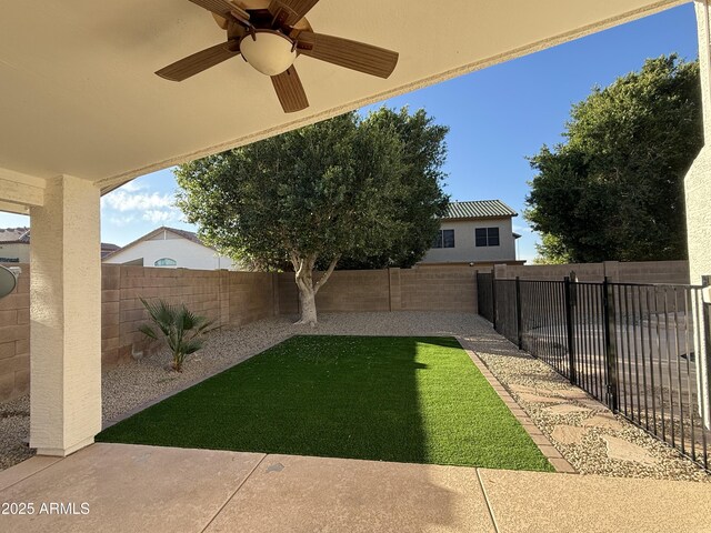 view of yard with a fenced backyard and a ceiling fan