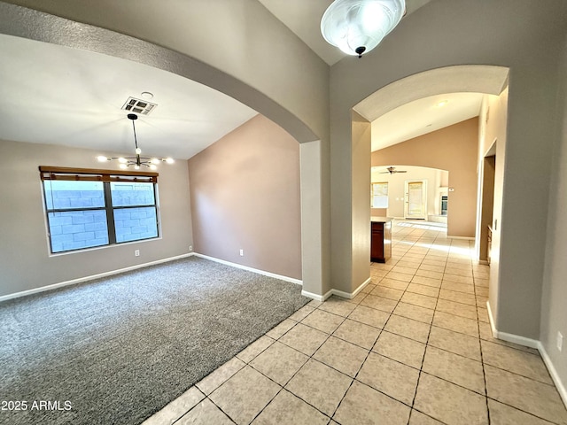 spare room with visible vents, light carpet, arched walkways, light tile patterned flooring, and baseboards