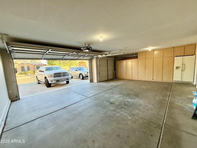 garage featuring white refrigerator with ice dispenser and a garage door opener