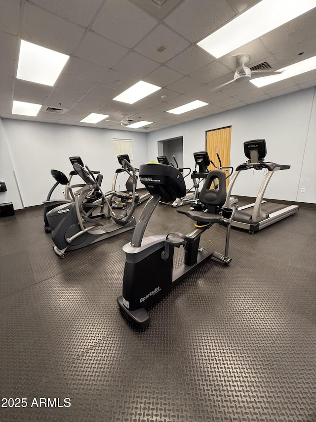 gym with visible vents, a paneled ceiling, and baseboards