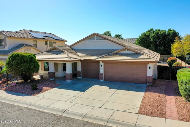 view of front of home with stucco siding, fence, concrete driveway, a garage, and a tiled roof