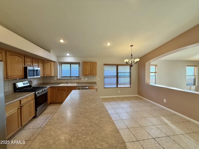 kitchen with tasteful backsplash, baseboards, light tile patterned floors, appliances with stainless steel finishes, and a notable chandelier