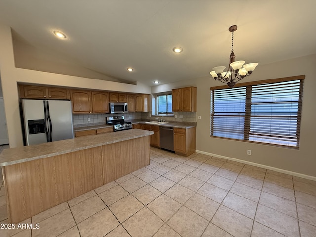 kitchen featuring a notable chandelier, a sink, appliances with stainless steel finishes, decorative backsplash, and lofted ceiling