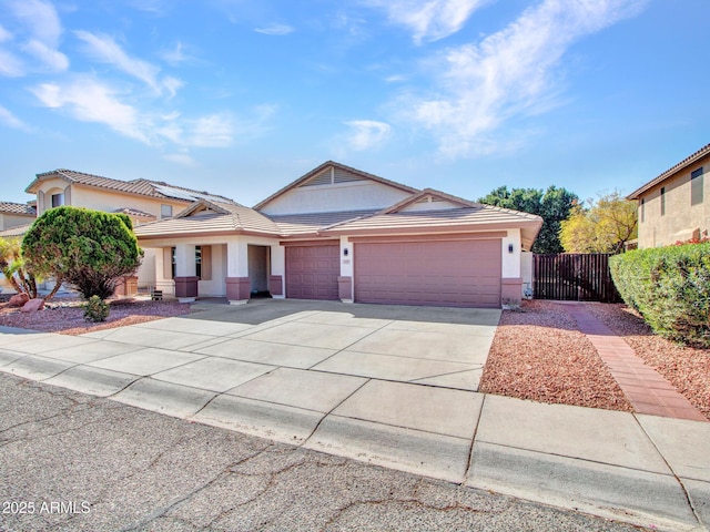 view of front of property featuring stucco siding, concrete driveway, an attached garage, and fence