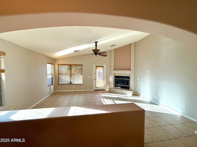 unfurnished living room with lofted ceiling, light tile patterned flooring, a ceiling fan, and a tile fireplace