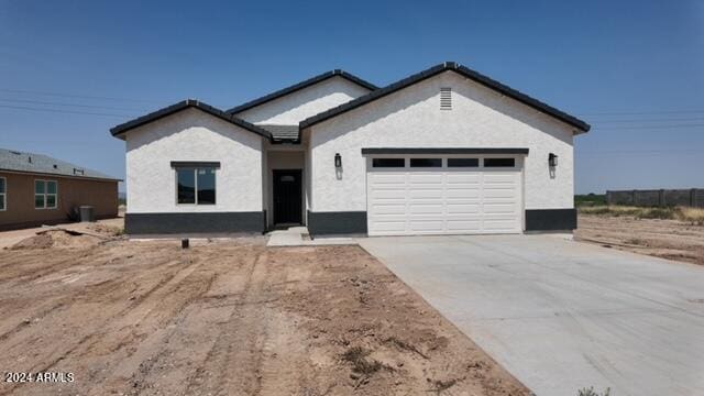 single story home featuring a garage, concrete driveway, a tile roof, and stucco siding