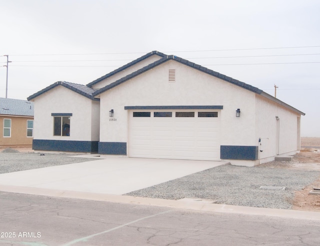 ranch-style house featuring concrete driveway, a tile roof, an attached garage, and stucco siding