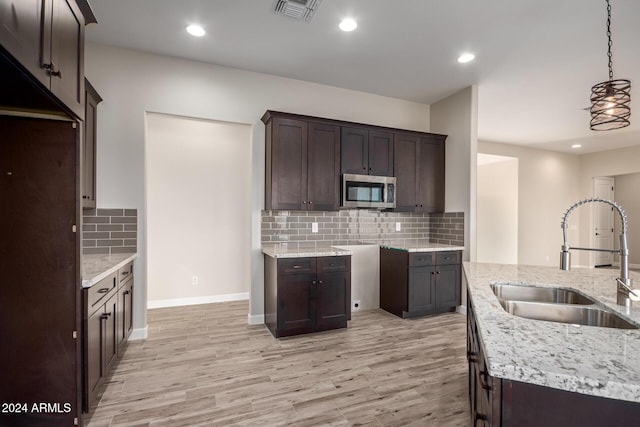 29785 N 203rd Dr, Wittmann, AZ 85361 - kitchen with a sink, stainless steel microwave, light stone counters, dark brown cabinets, and recessed lighting