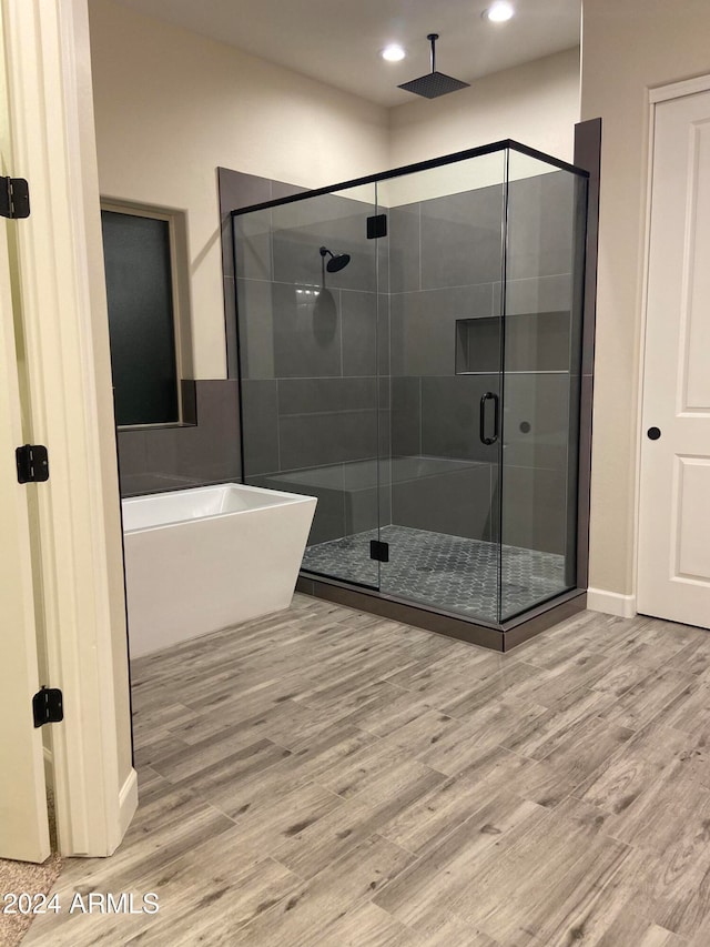 bathroom with hardwood / wood-style flooring and separate shower and tub