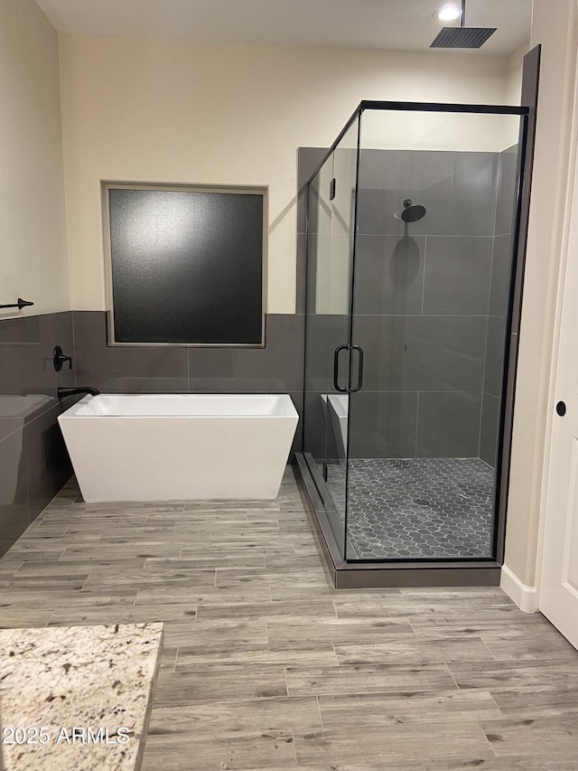 29785 N 203rd Dr, Wittmann, AZ 85361 - bathroom with wood finished floors, a shower stall, a freestanding bath, tile walls, and wainscoting