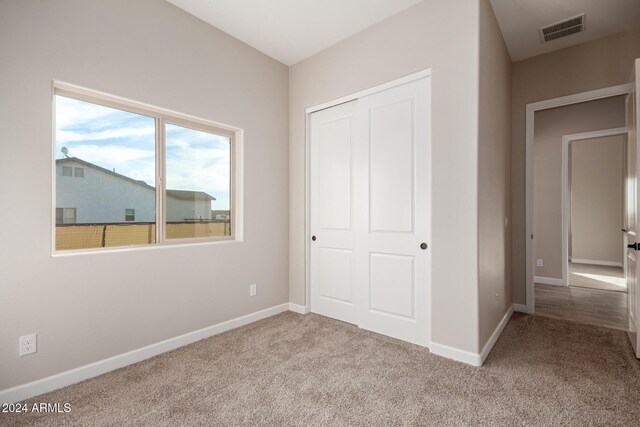 unfurnished bedroom featuring a closet and light colored carpet