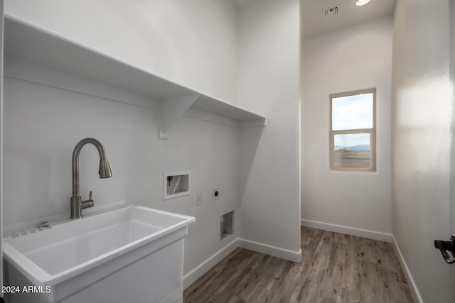 laundry area with sink, hookup for an electric dryer, light wood-type flooring, and hookup for a washing machine