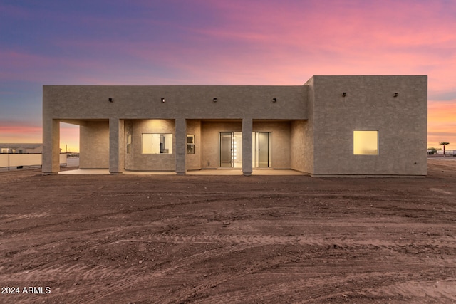 back house at dusk with a patio area