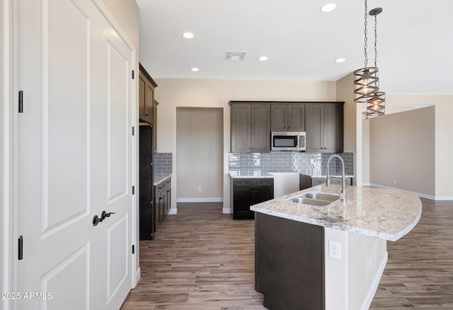 29785 N 203rd Dr, Wittmann, AZ 85361 - kitchen with stainless steel microwave, a sink, light wood-type flooring, decorative backsplash, and dark brown cabinetry