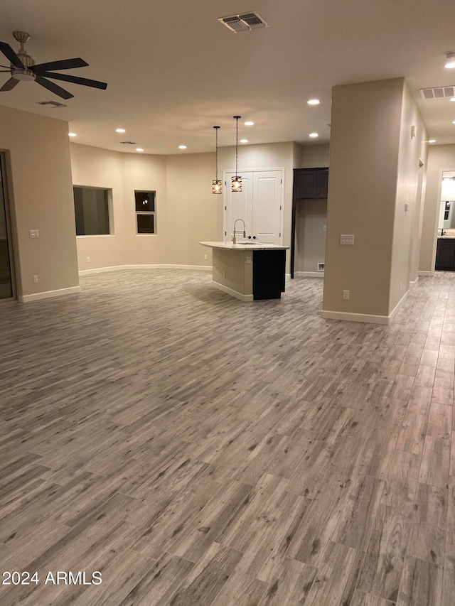 unfurnished living room with ceiling fan, hardwood / wood-style flooring, and sink