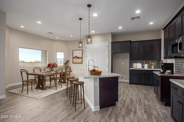 29785 N 203rd Dr, Wittmann, AZ 85361 - kitchen featuring stainless steel microwave, light stone countertops, light wood-style floors, and recessed lighting
