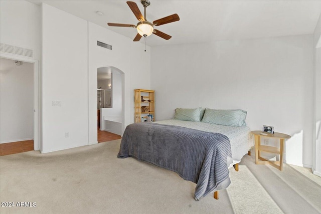 carpeted bedroom featuring high vaulted ceiling, ensuite bath, and ceiling fan