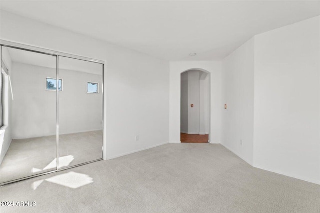 unfurnished bedroom with a closet and light colored carpet