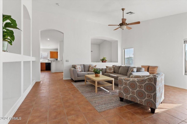 living room with ceiling fan, tile patterned flooring, and a towering ceiling