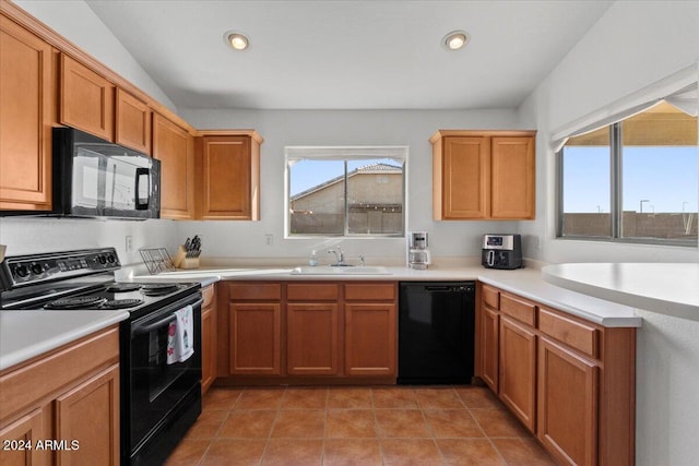 kitchen featuring black appliances, lofted ceiling, light tile patterned floors, and sink