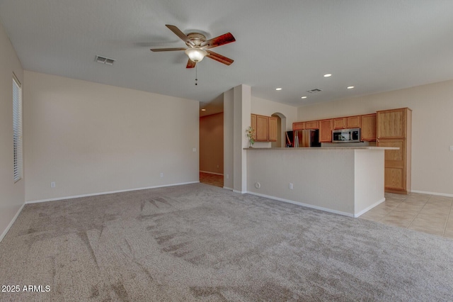 unfurnished living room featuring ceiling fan and light colored carpet