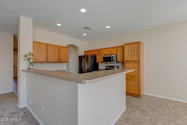 kitchen featuring appliances with stainless steel finishes, light tile patterned floors, and kitchen peninsula