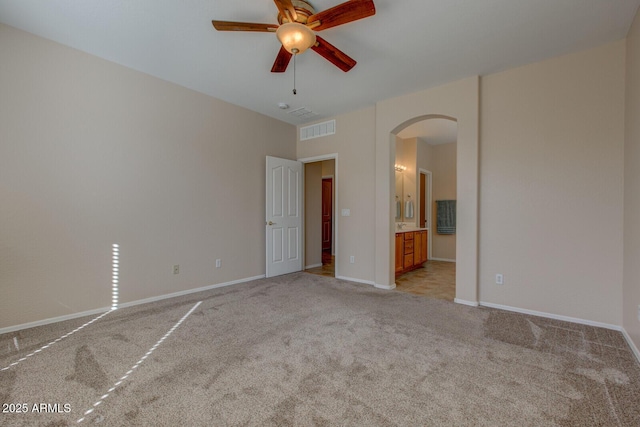 unfurnished bedroom with ceiling fan, ensuite bathroom, and light colored carpet