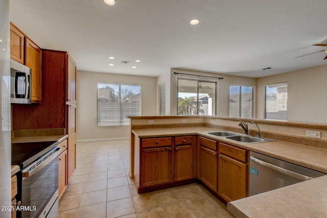 kitchen with stainless steel appliances, sink, light tile patterned floors, and ceiling fan