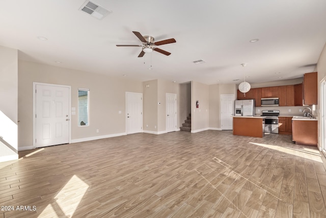 unfurnished living room with sink, ceiling fan, and light hardwood / wood-style flooring