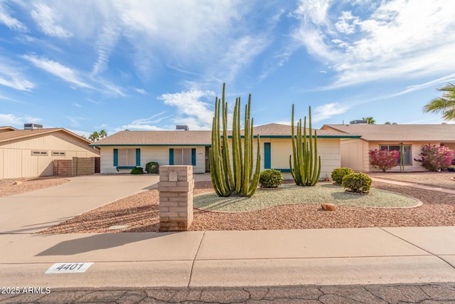 ranch-style house featuring fence and concrete driveway