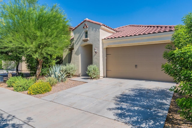 mediterranean / spanish home with concrete driveway, an attached garage, a tile roof, and stucco siding