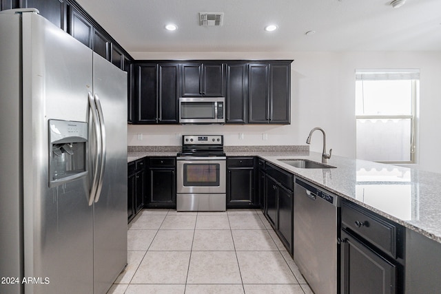 kitchen featuring light tile patterned floors, appliances with stainless steel finishes, sink, and light stone countertops