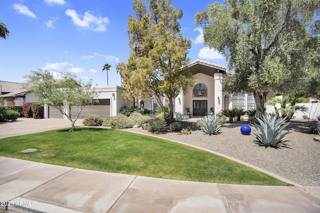 mediterranean / spanish home featuring driveway, a front lawn, a garage, and stucco siding