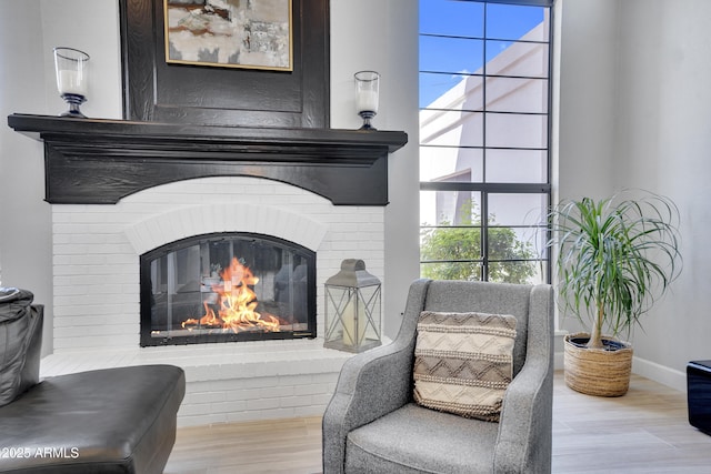 living area with a fireplace, baseboards, and wood finished floors
