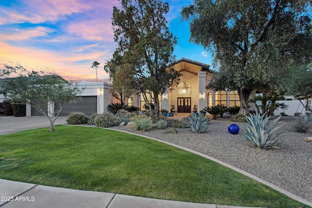 view of front of home with a lawn, stucco siding, french doors, and an attached garage