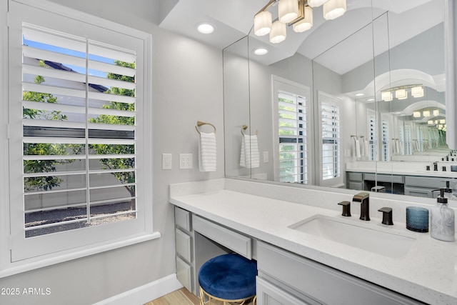 bathroom featuring baseboards, recessed lighting, vanity, and a notable chandelier