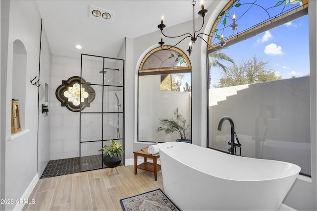 full bath featuring a walk in shower, an inviting chandelier, recessed lighting, wood finished floors, and a freestanding bath