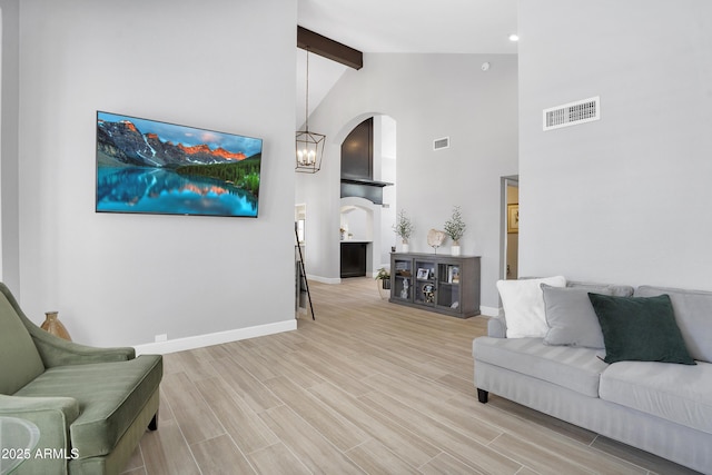 living room featuring visible vents, arched walkways, beam ceiling, and wood tiled floor