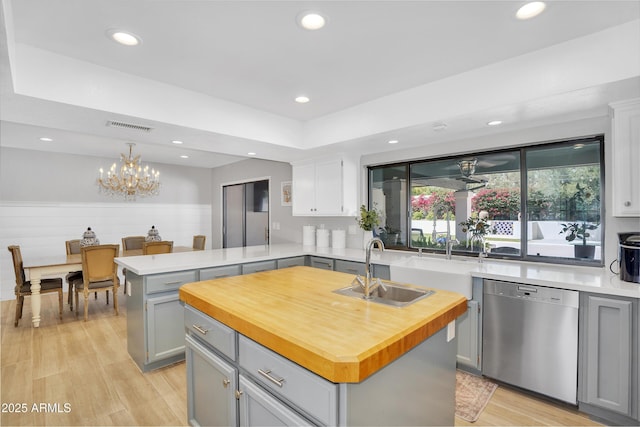 kitchen featuring gray cabinetry, wood counters, dishwasher, and a sink