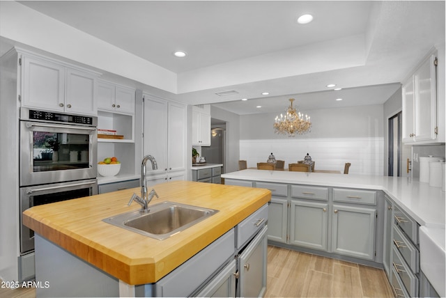 kitchen with wood counters, a sink, and gray cabinets