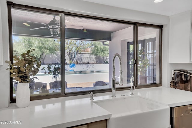 kitchen with light countertops, dishwasher, a sink, and a ceiling fan
